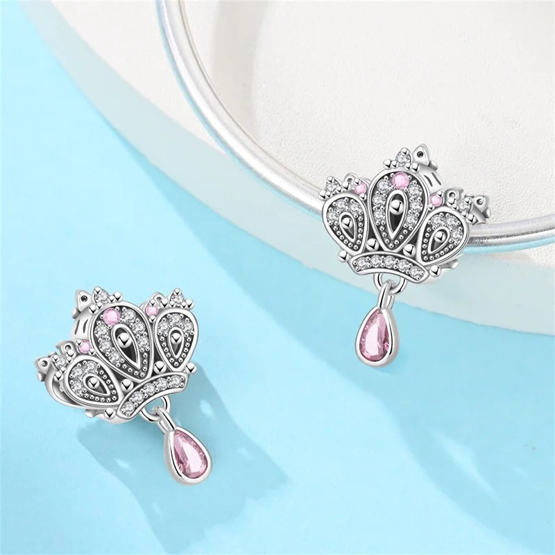 Pair of silver earrings with pink gemstones on a light blue background. pandora style