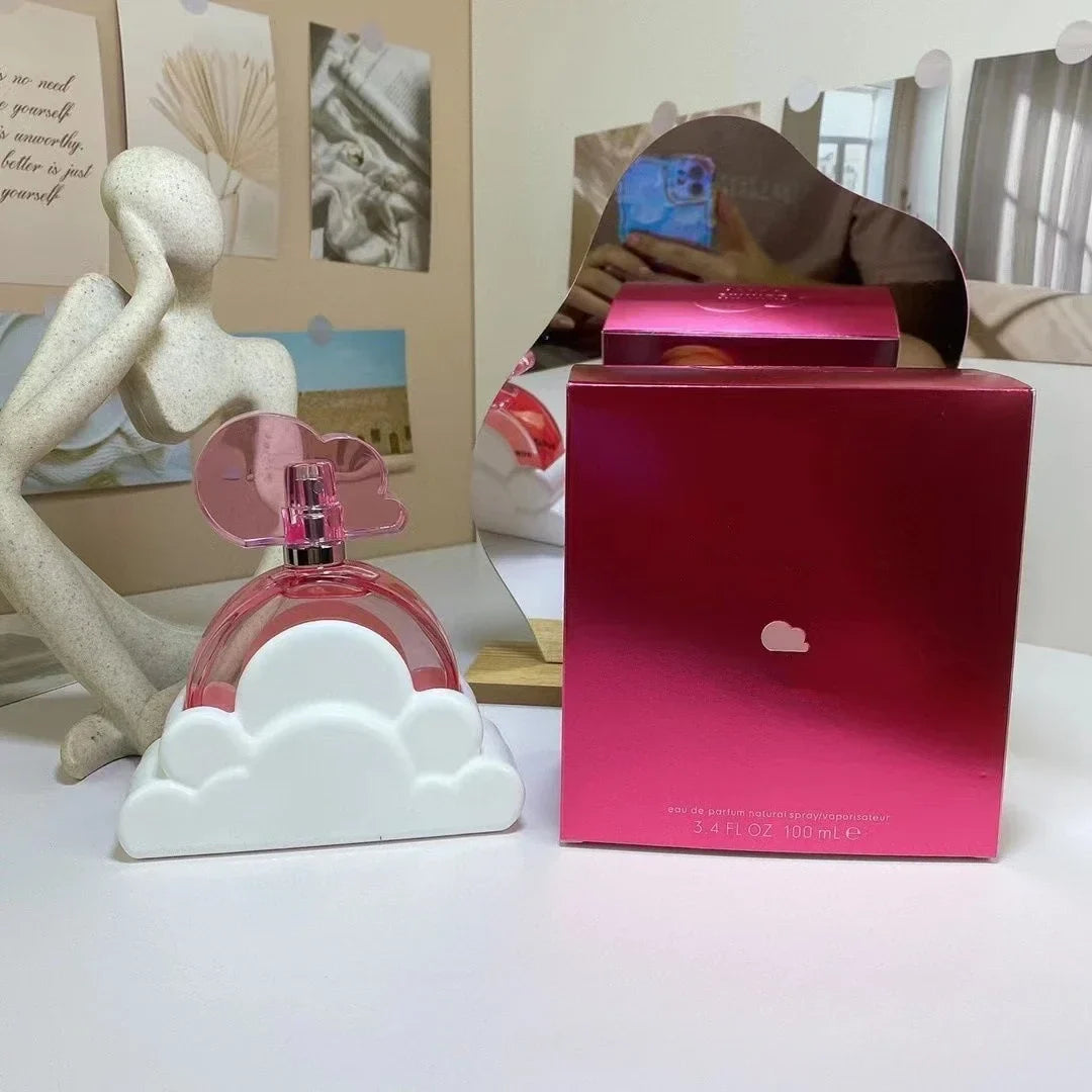 Pink perfume bottle and box on a surface with decorative items in the background