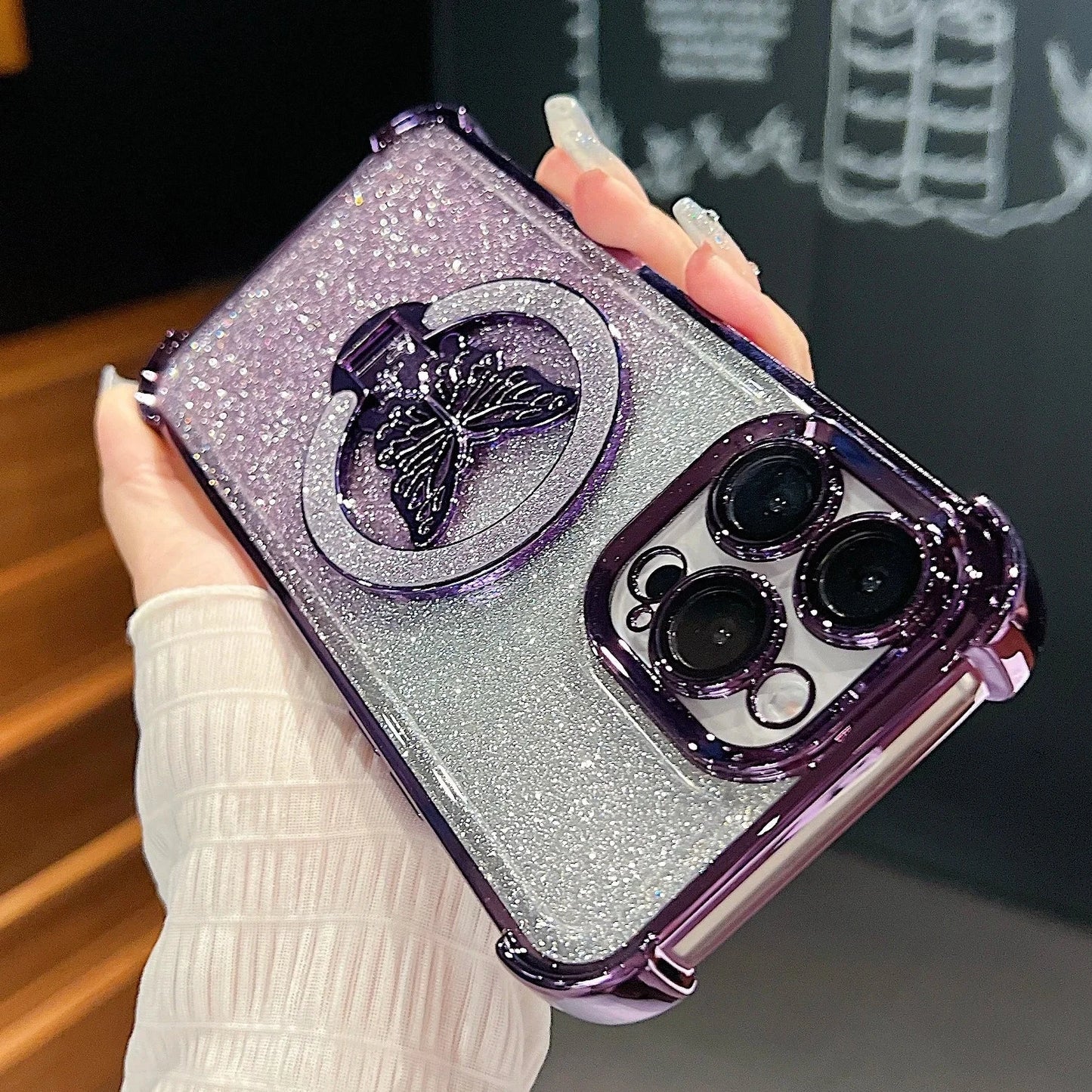 Phone case with butterfly design held by a hand against a blurred background