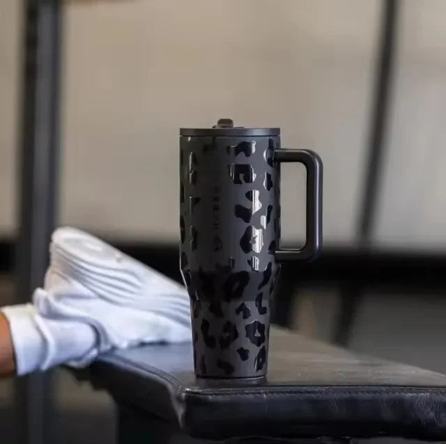 Black leopard print HydroJug Gobelet 40OZ Voyageur Thermos placed on a gym bench, showcasing its stylish and durable design.