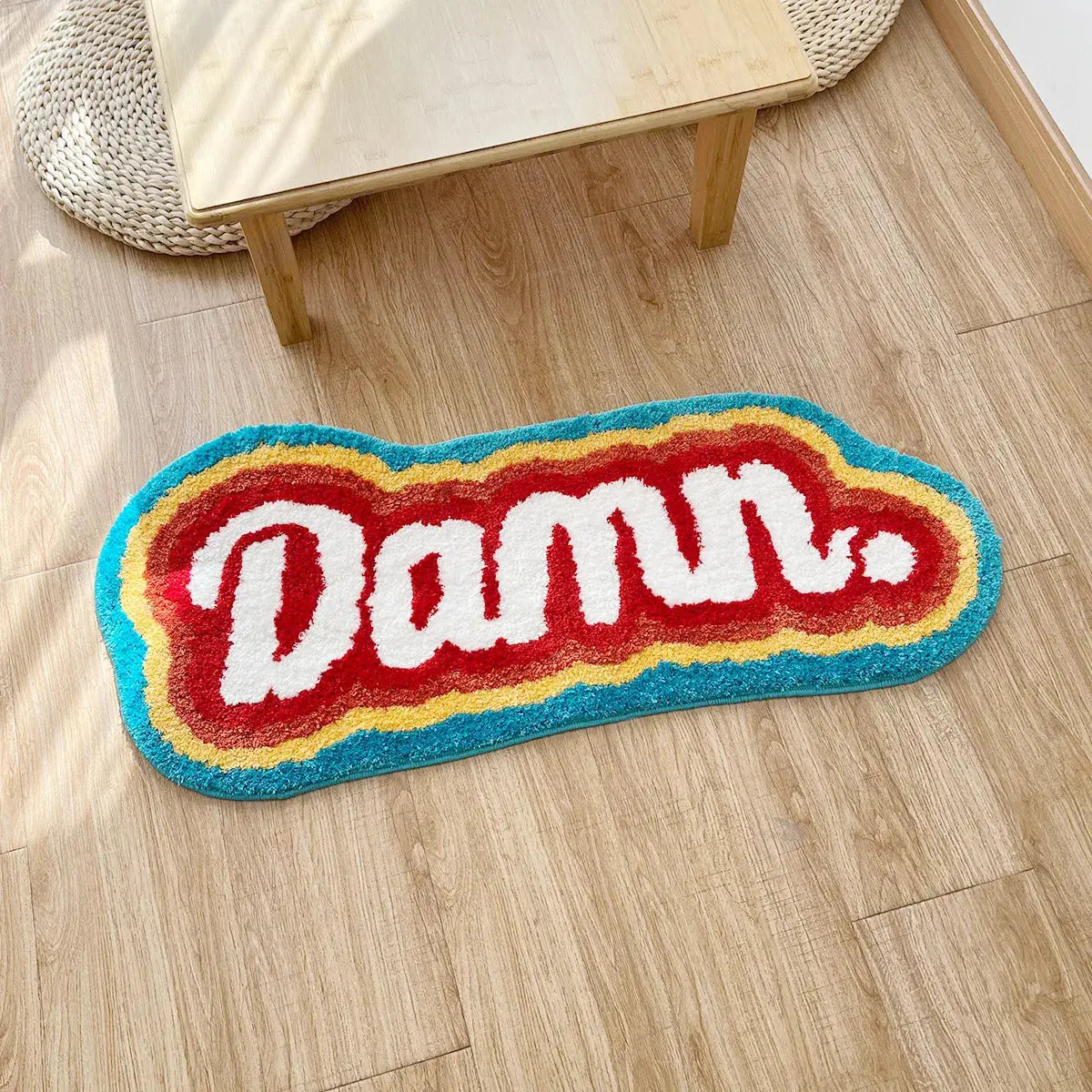 Colorful rug with 'Damu' text on a wooden floor