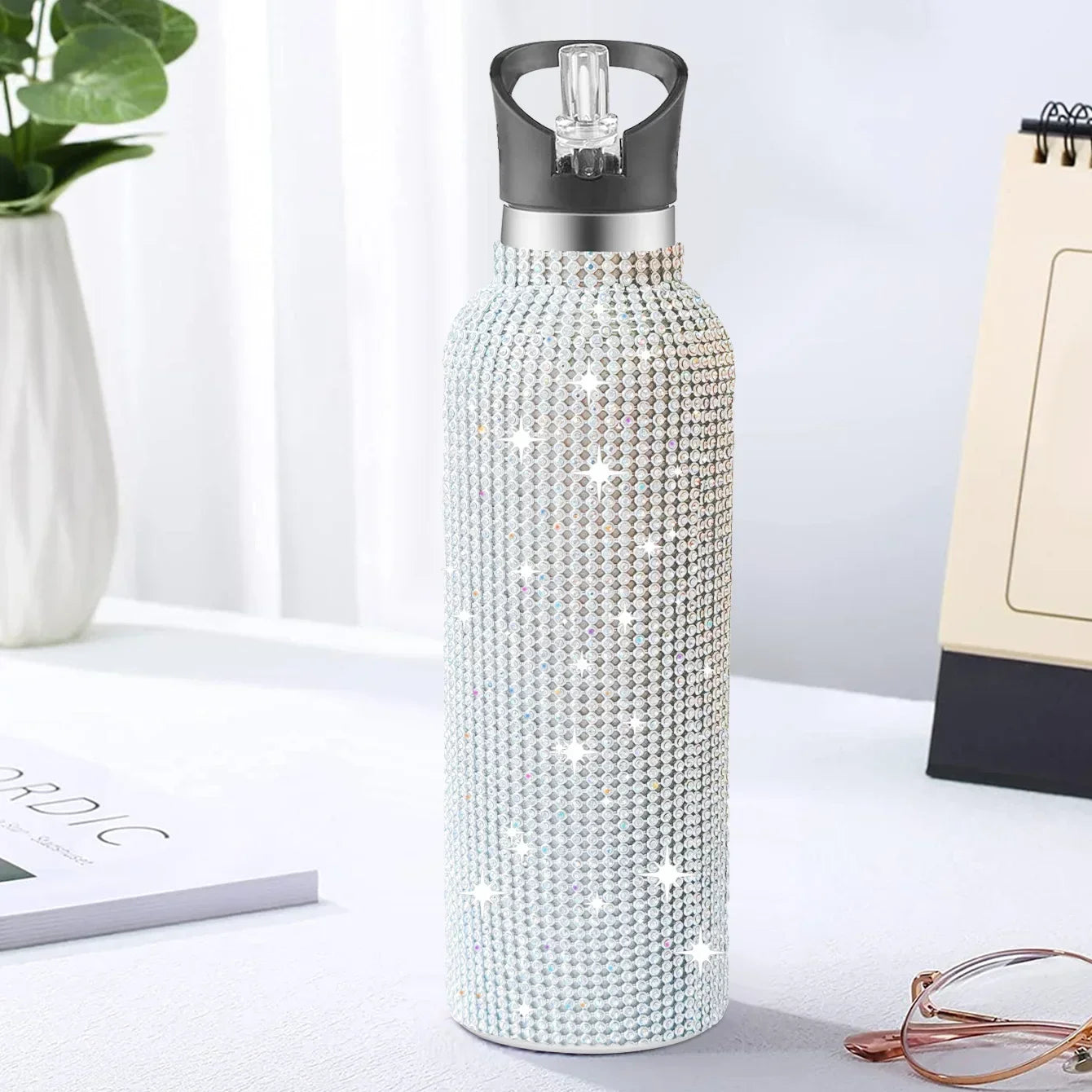 Decorative water bottle with rhinestone embellishments on a white surface.