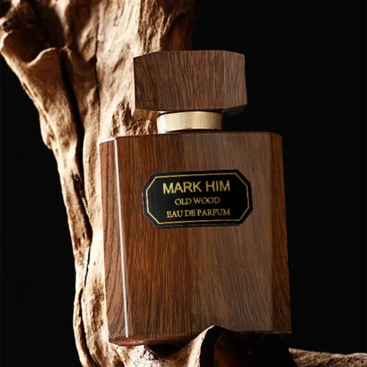 Wooden perfume bottle labeled 'Mark Him Old Wood Eau de Parfum' against a dark background.