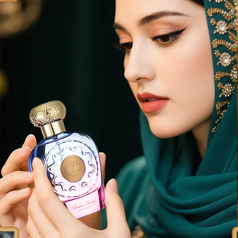 Woman holding a perfume bottle with a dark background