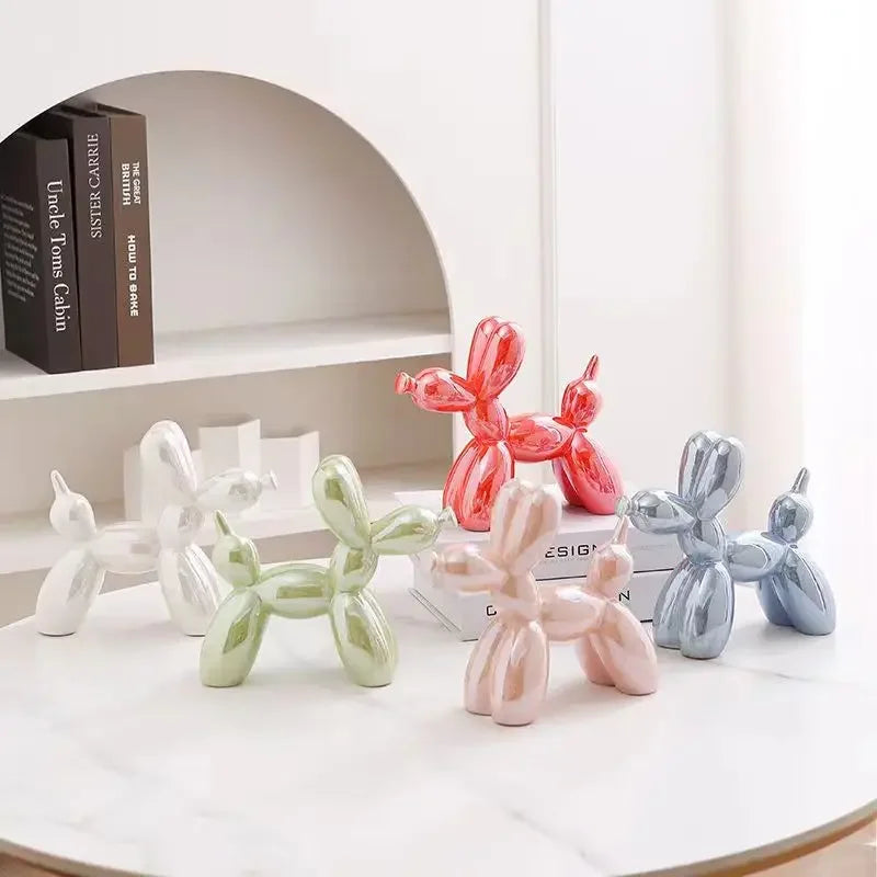 Colorful metallic balloon dog sculptures on a table with a minimal background