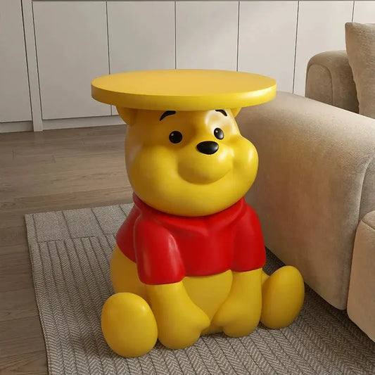 Whinnie the Pooh Yellow bear-shaped stool with a round top in a living room setting.