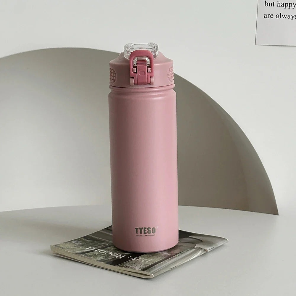 TYESO pink thermos bottle with straw on a magazine. Stylish, BPA-free, and insulated for hot or cold beverages.