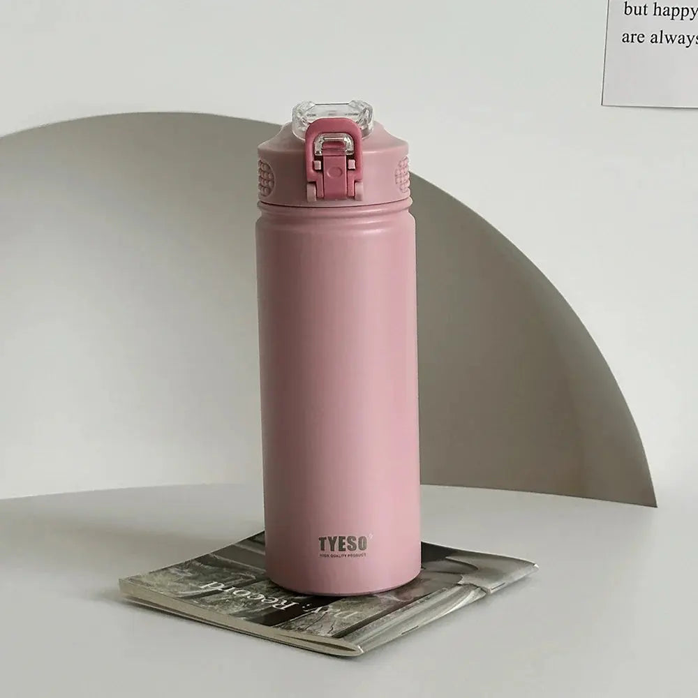 TYESO pink thermos bottle with straw on a magazine. Stylish, BPA-free, and insulated for hot or cold beverages.