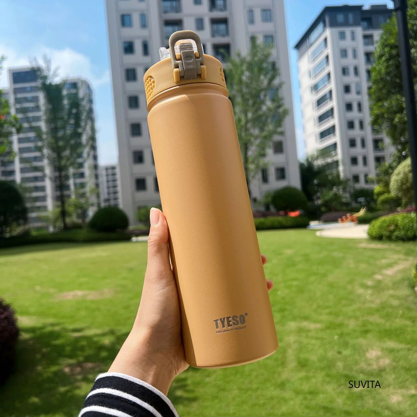 TYESO yellow thermos bottle with straw held outdoors. BPA-free and insulated to maintain drink temperature.