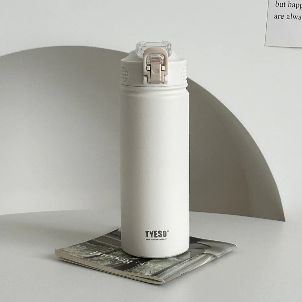 TYESO white thermos bottle with straw on a magazine. Leak-proof and BPA-free, perfect for everyday hydration.