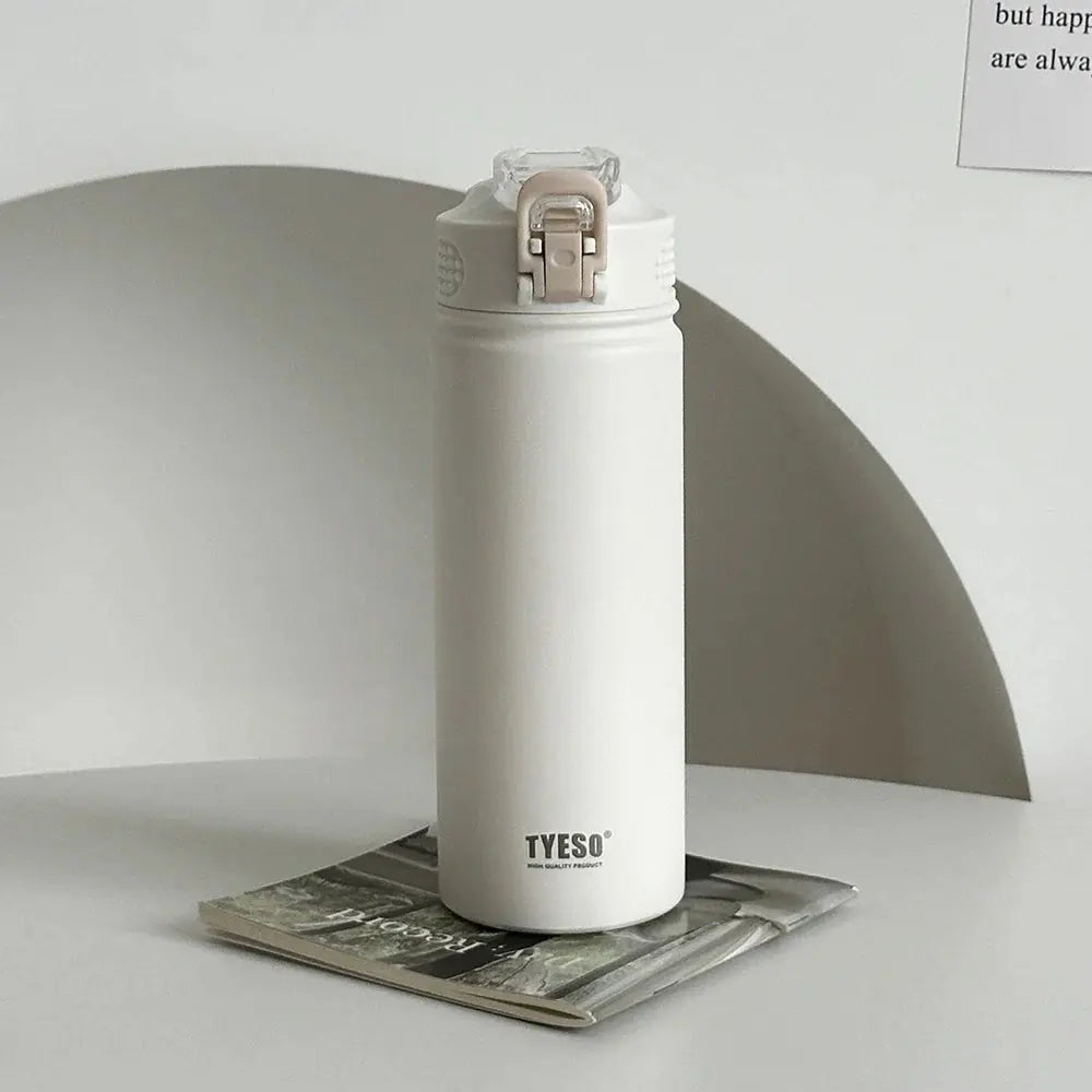 TYESO white thermos bottle with straw on a magazine. Leak-proof and BPA-free, perfect for everyday hydration.