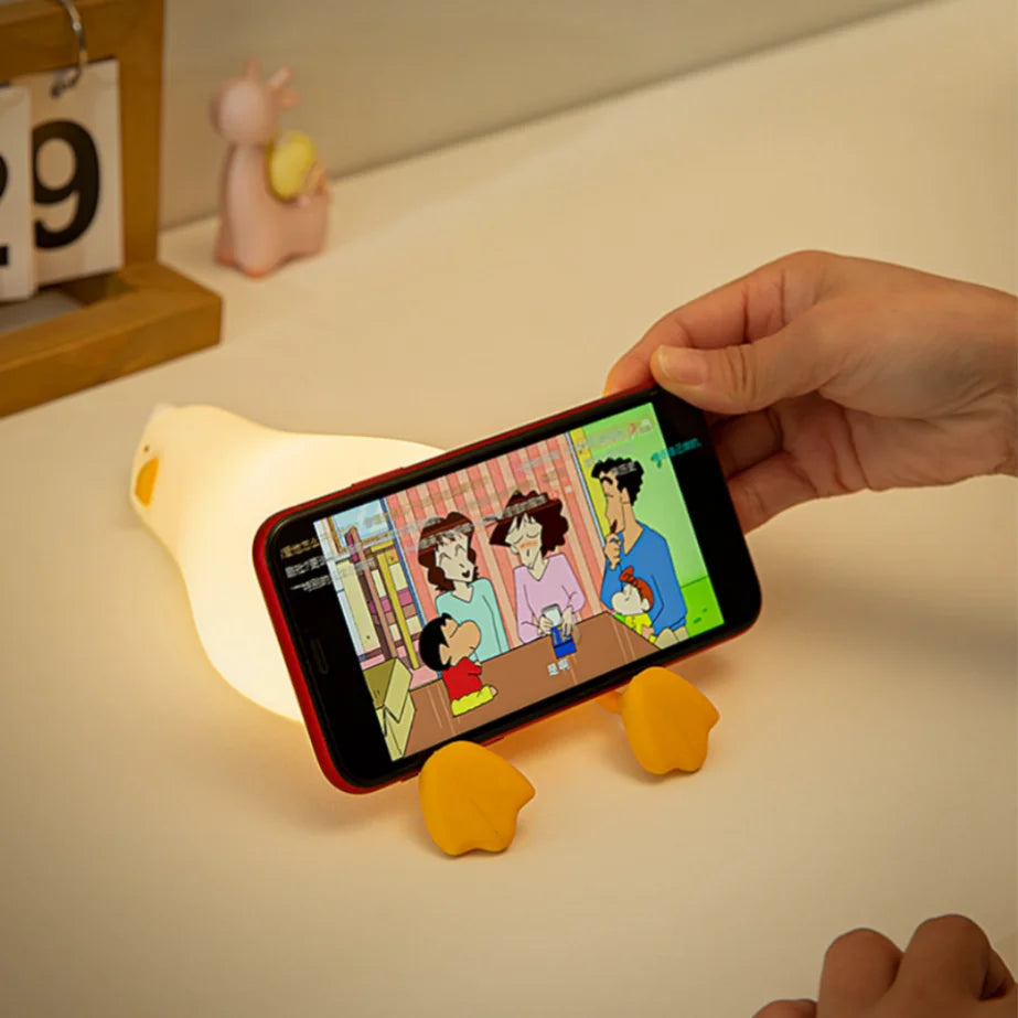 Hand holding a smartphone with a cartoon displayed on a small lamp