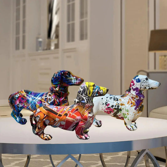 Three colorful dachshund figurines on a table with a blurred indoor background dashhound