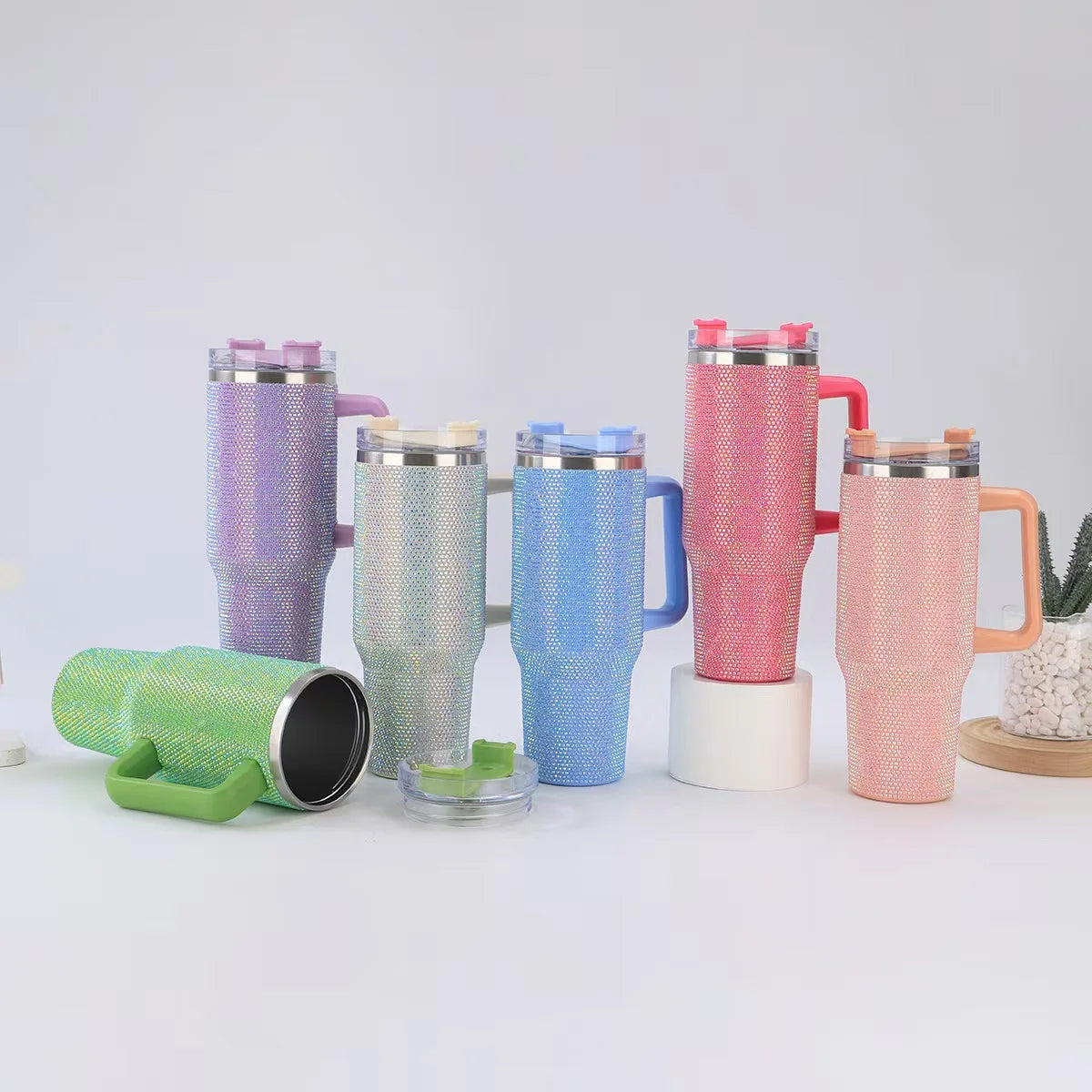 Set of colorful tumblers with mesh sleeves on a white surface