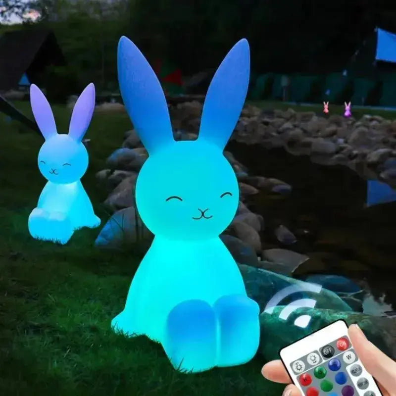 Two glowing rabbit-shaped lights with a remote control on a dark outdoor background.