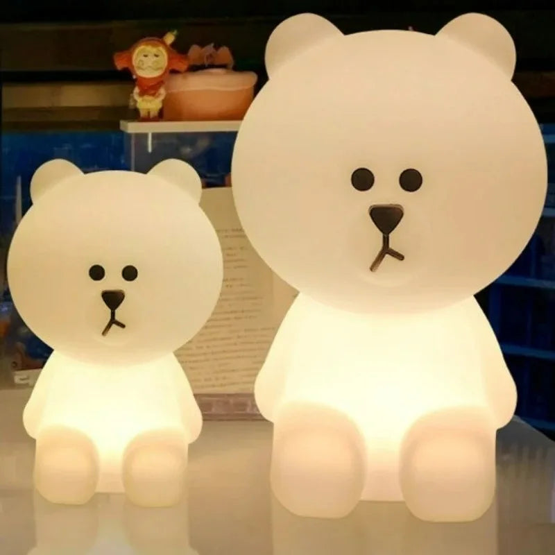 Two white bear-shaped night lights on a reflective surface with a blurred background.