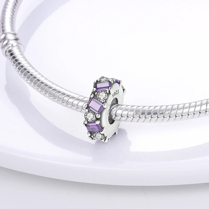Silver bracelet with a purple charm on a white background