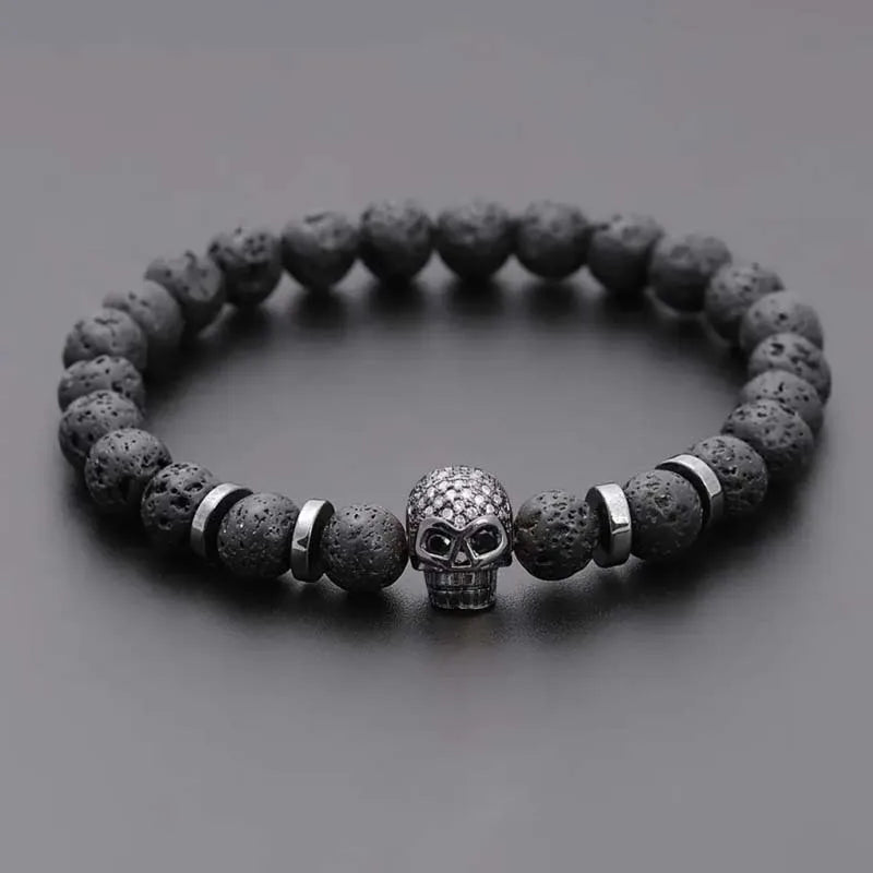 Bracelet with dark beads and a skull charm on a gray background