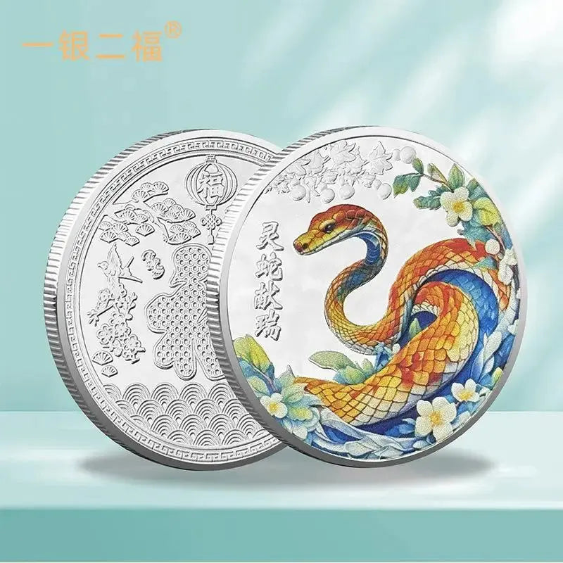 A collectible coin with a 3D relief design of a snake and floral patterns, predominantly in gold and silver colors.