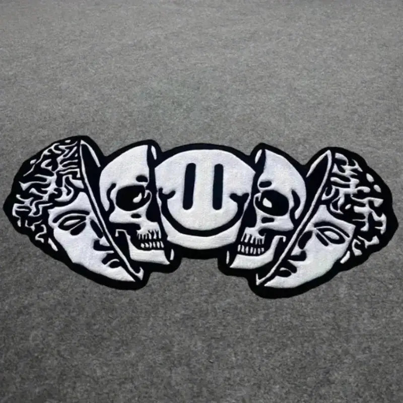 Silver skull and leaf design on a gray background