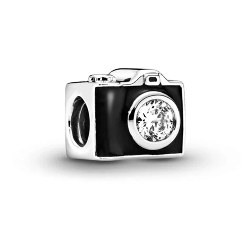 Camera-shaped charm with a clear gemstone on a white background