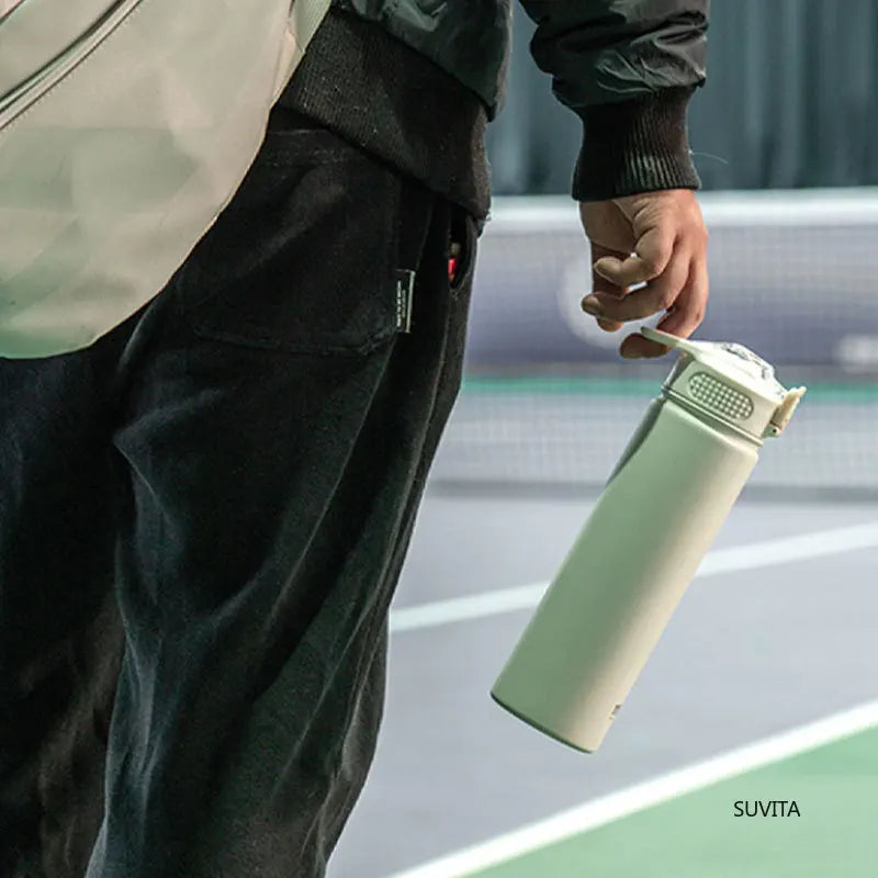 Person holding TYESO white thermos bottle with straw by the loop handle. Ideal for sports, gym, or outdoor activities.
