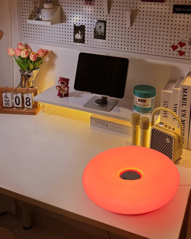 Orange glowing disc on a desk with decor items including a teddy bear and small computer monitor.