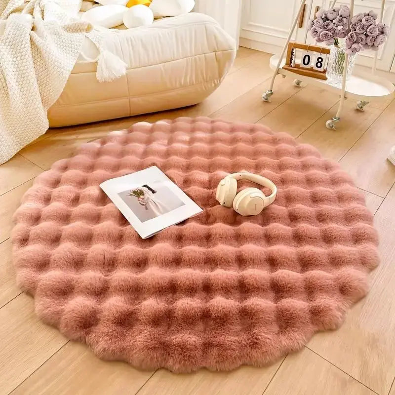Round pink rug on a wooden floor with a photo and headphones on top, in a cozy living room setting.
