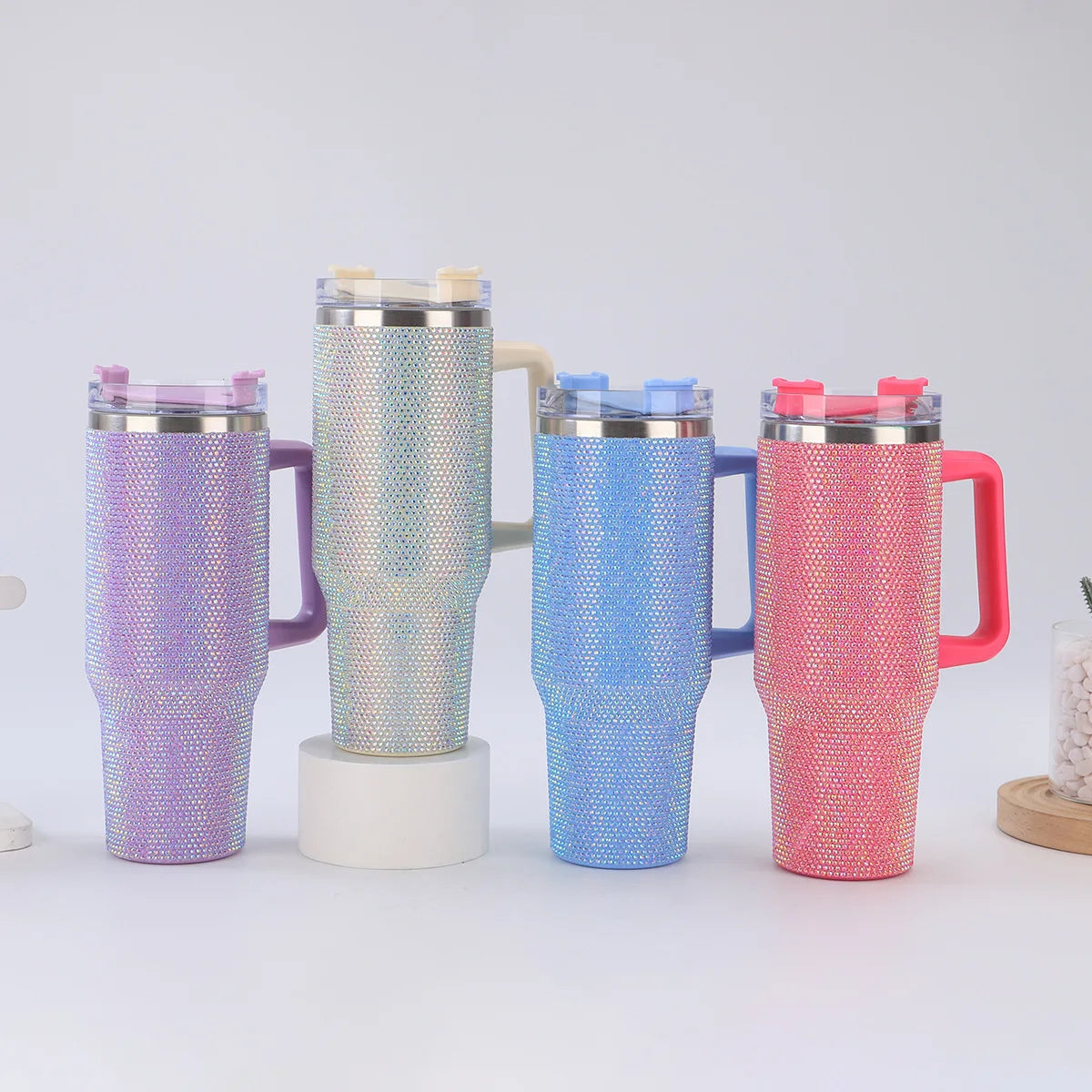 Four insulated mugs with colorful rhinestone sleeves on a white background