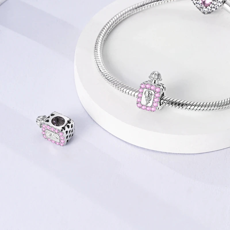 Silver bracelet with pink perfume bottle charm on a white surface. pandora style