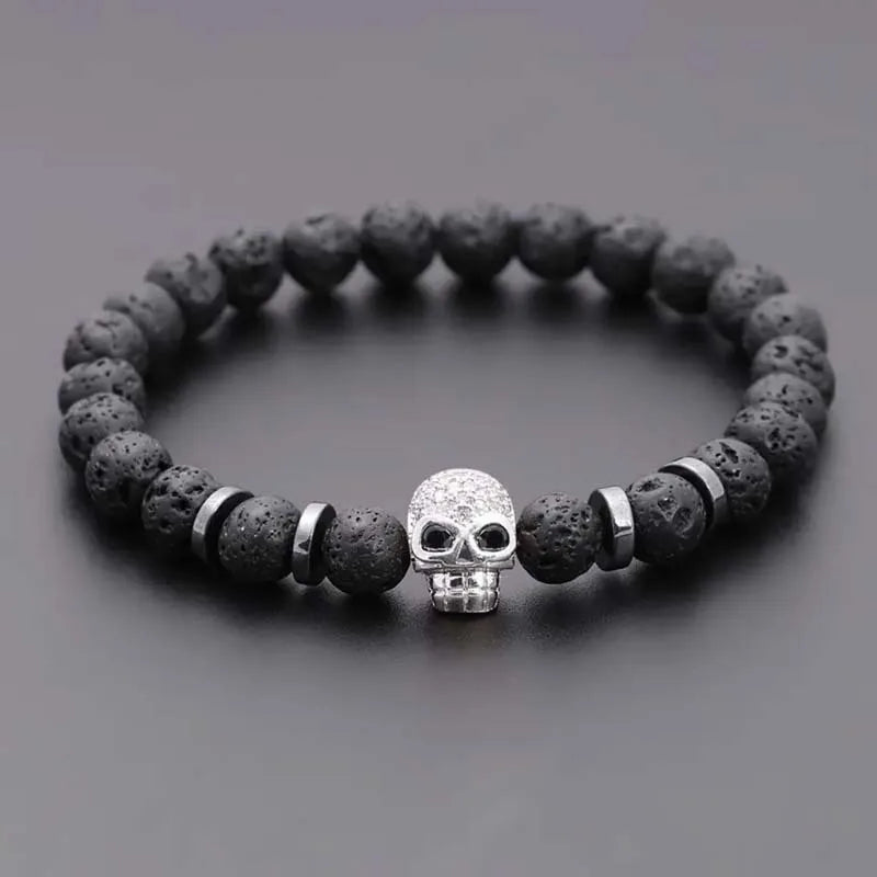 Black beaded bracelet with a silver skull charm on a gray background