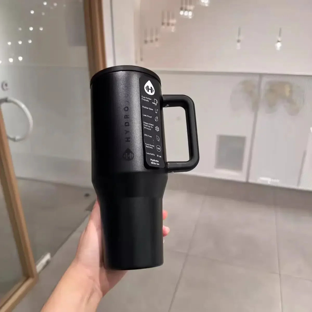 Matte black HydroJug Gobelet 40OZ Voyageur Thermos held in hand, emphasizing minimalist design and ergonomic handle.