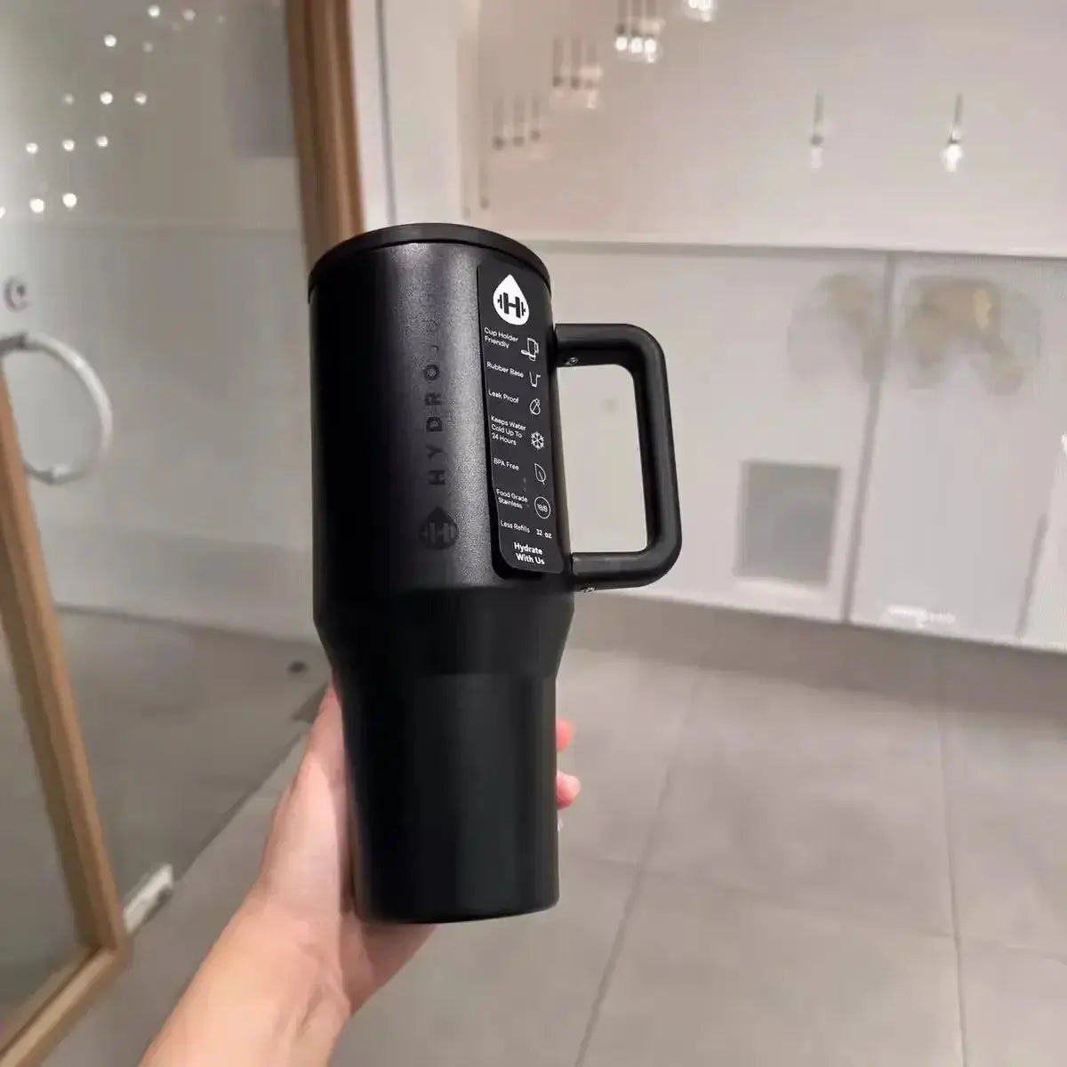 Matte black HydroJug Gobelet 40OZ Voyageur Thermos held in hand, emphasizing minimalist design and ergonomic handle.