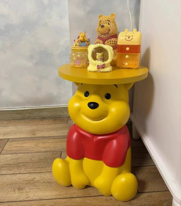 Whinnie the Pooh kids Yellow bear-shaped stool with small bear figurines on a wooden floor.