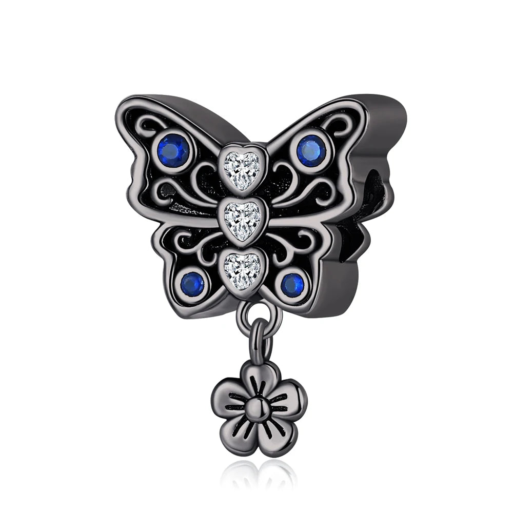 Butterfly-shaped pendant with blue gemstones and a flower charm on a white background. pandora style charm pendant. Gothic style