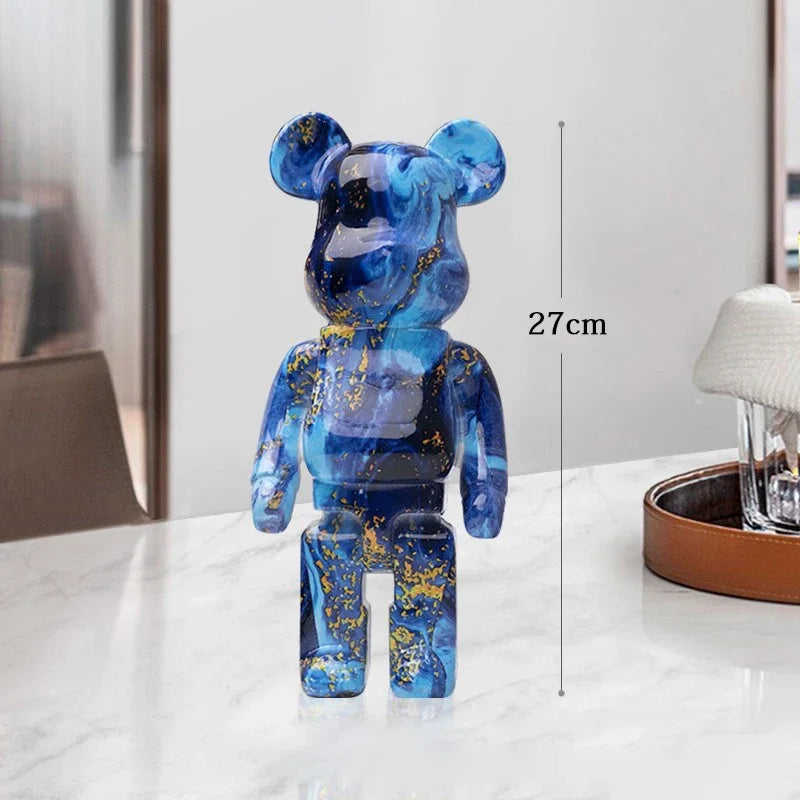 Blue and gold bear-like figurine on a white surface with a measurement label indicating its height. be@rbrick collectable