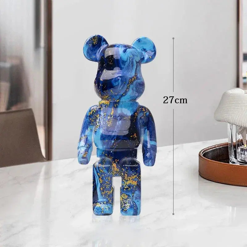 Blue and gold bear-like figurine on a white surface with a measurement label indicating its height. be@rbrick collectable