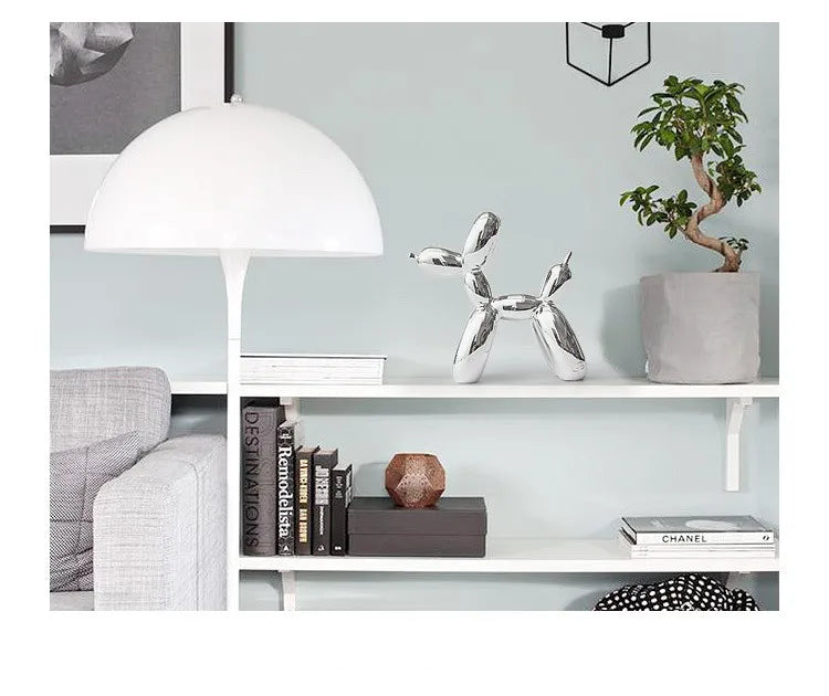 Modern living room with a white lamp, decorative dog sculpture, books, and a plant.