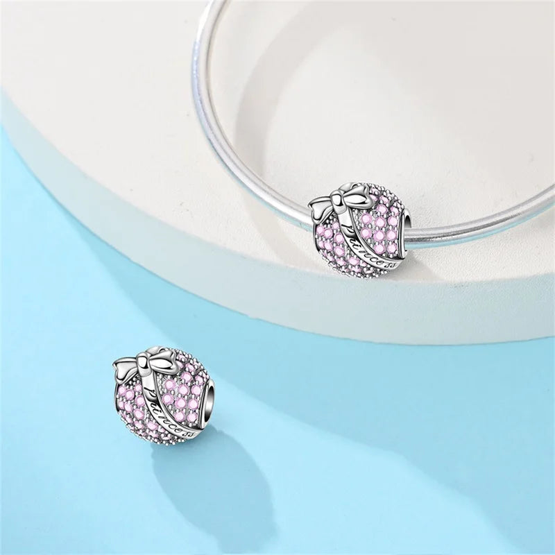 Two pink jewelry charms on a light blue background. pandora style