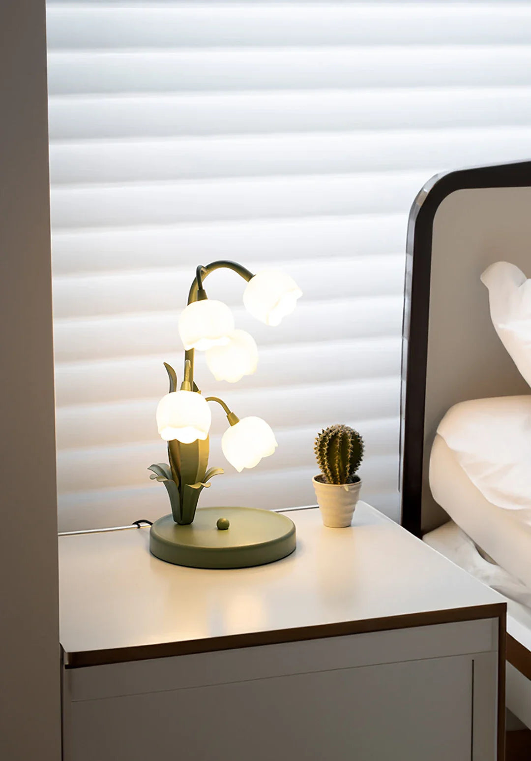 Modern lamp with spherical lights on a nightstand next to a bed