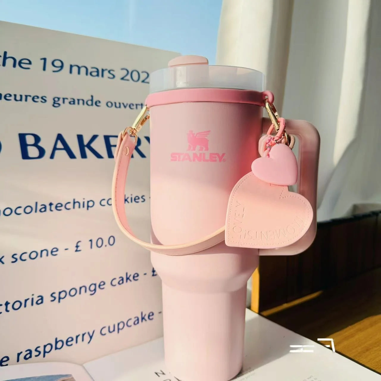 Pink Stanley water bottle with heart-shaped keychain on a menu background