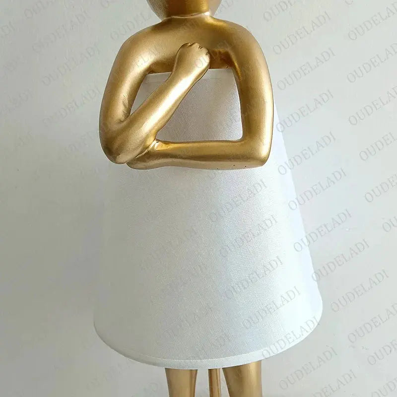 Decorative lamp with gold base and white shade on a light gray background