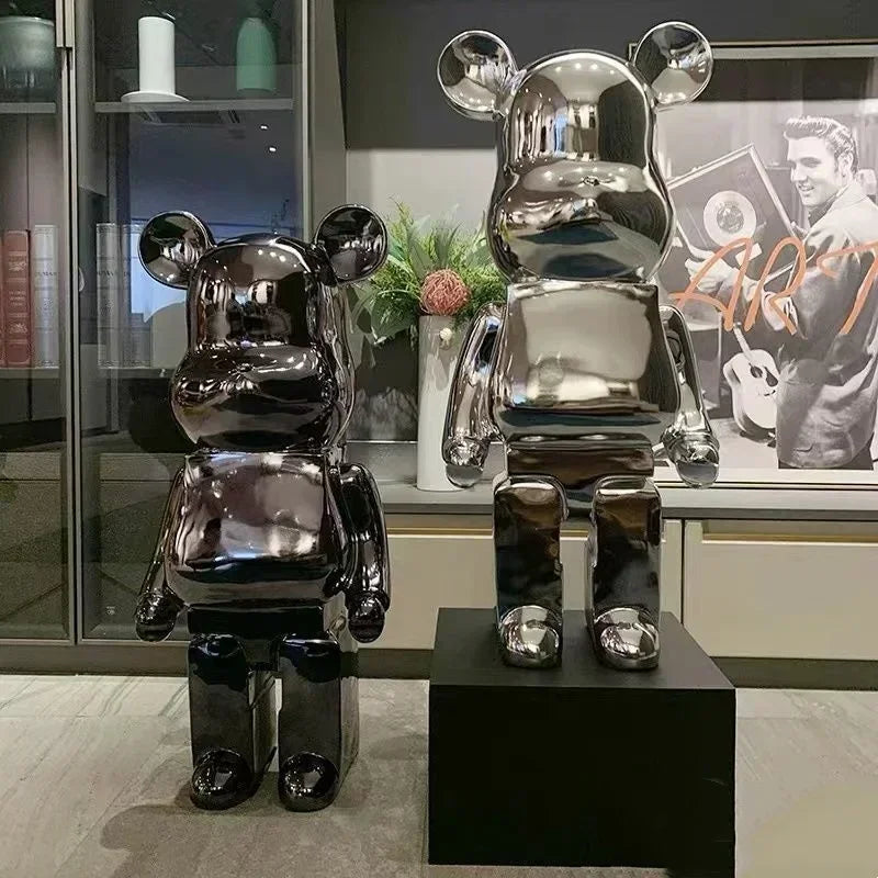 Two metallic bear sculptures on black stands in a modern interior setting. bearbrick collectable