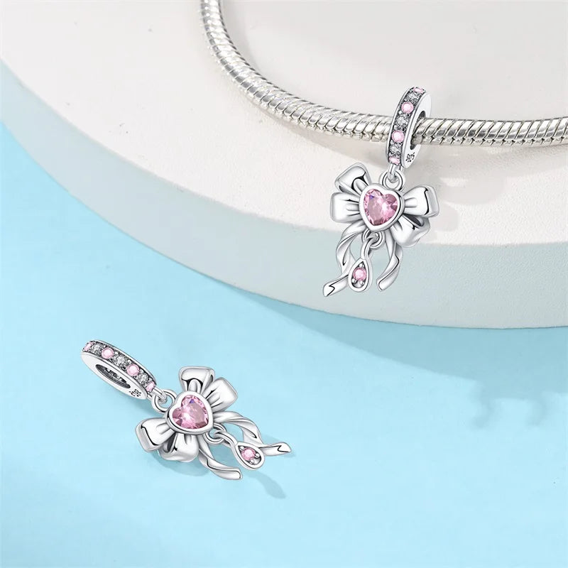 Silver pendants with pink gemstones on a light blue background. pandora style