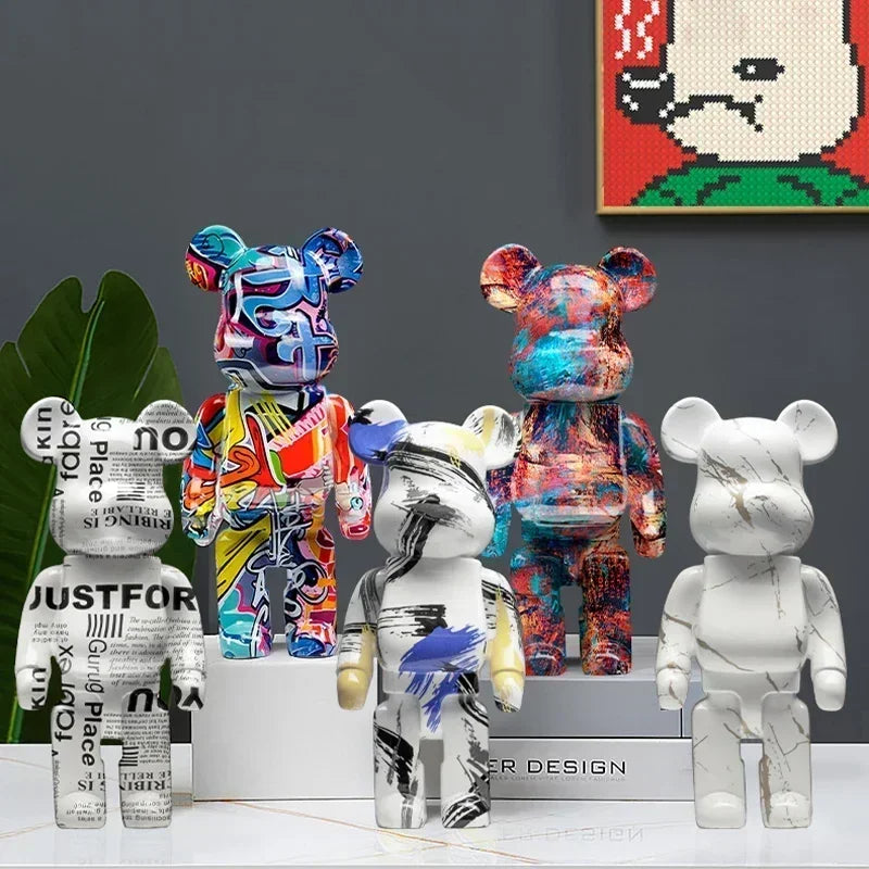 Collection of colorful and white bear-like figurines on a gray surface with a pixelated art piece in the background. be@rbrick collectable