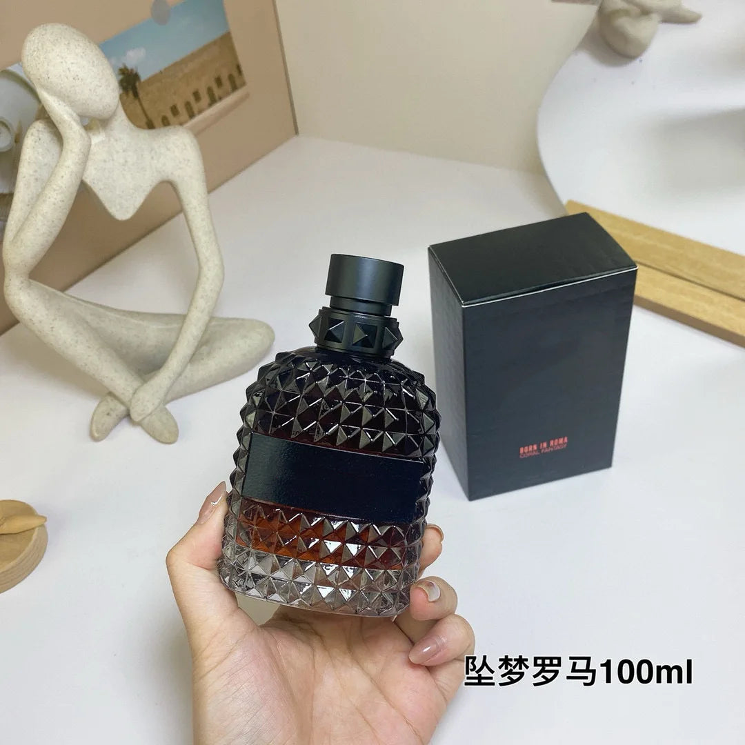 Valentino Black diamond-patterned perfume bottle held by a hand with packaging on a white surface.