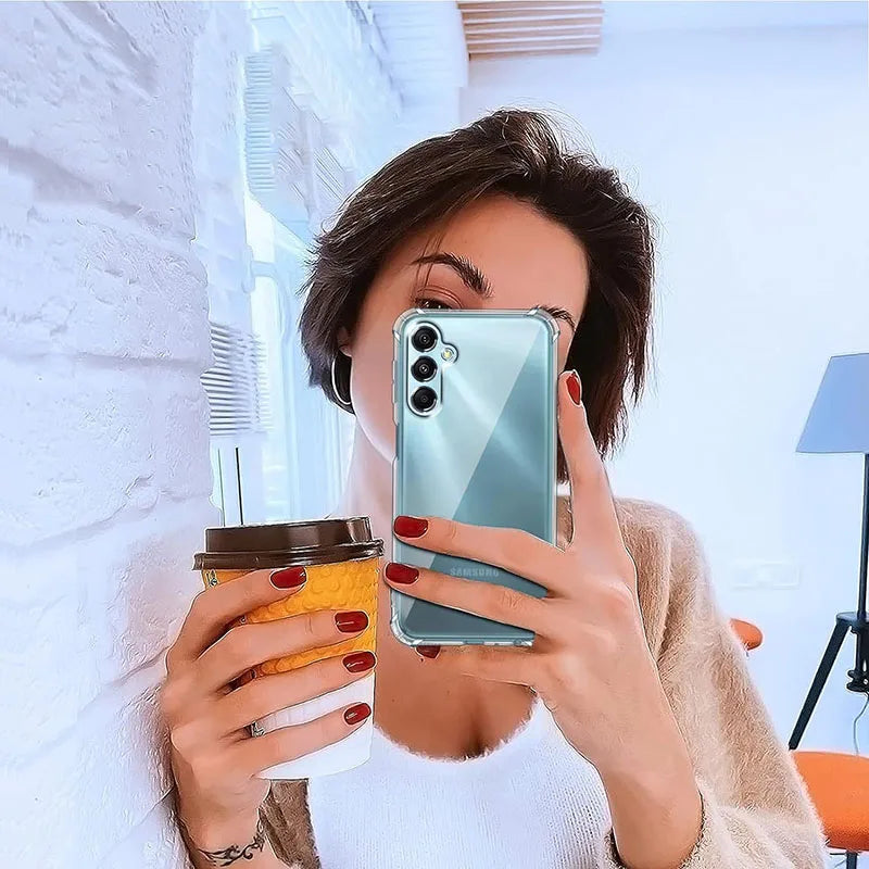 Woman taking a mirror selfie with a phone, holding a coffee cup.