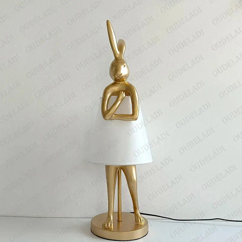 Decorative lamp shaped like a rabbit with a white base and gold body on a light gray background.