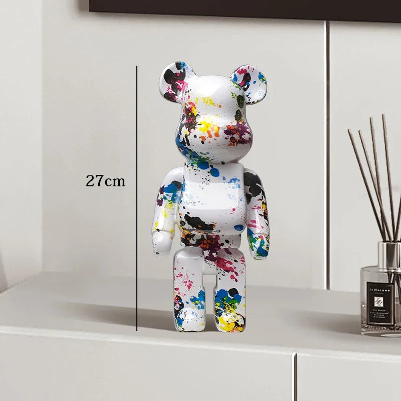 Colorful bear figurine with paint splashes on a white surface next to a diffuser. be@rbrick collectable
