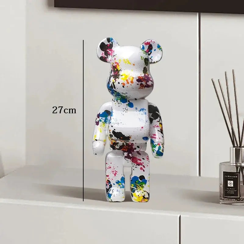 Colorful bear figurine with paint splashes on a white surface next to a diffuser. be@rbrick collectable